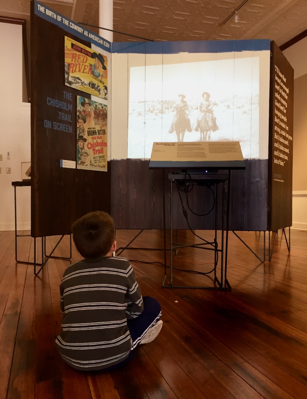 Video of Chisholm Trail route projected onto raw wooden panel structure